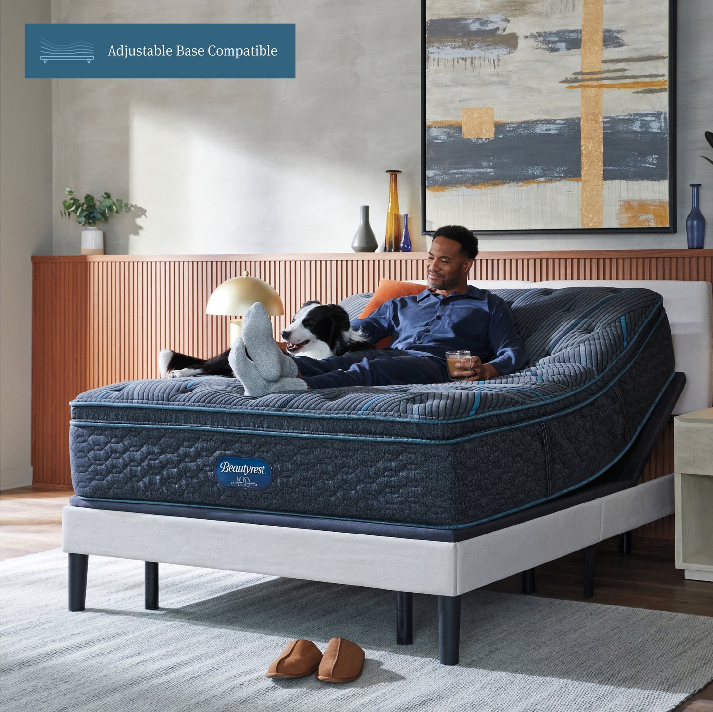 Man sitting on a Beautyrest mattress sitting on an adjustable frame petting his dog.