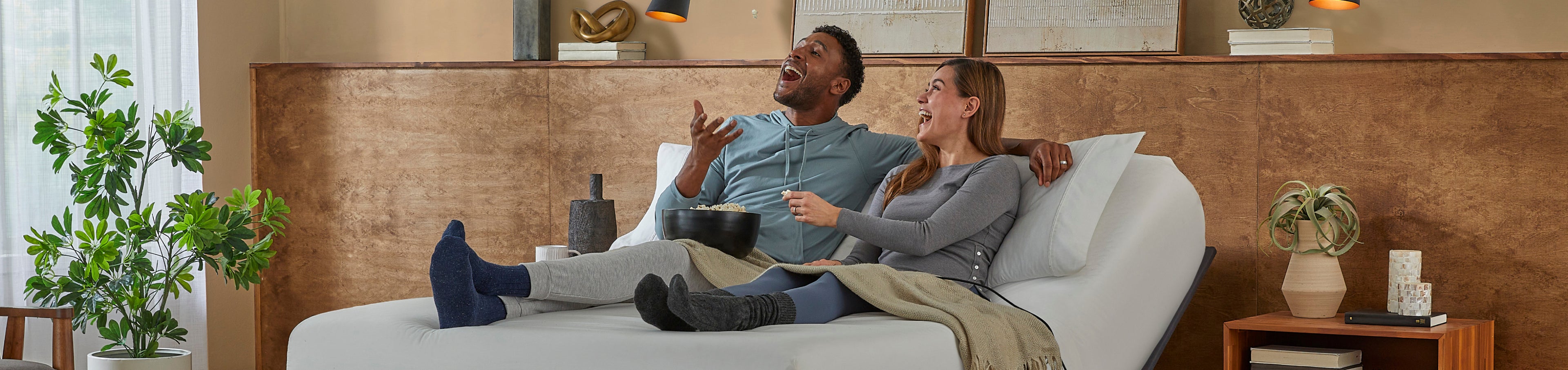 Man and woman sitting on a white mattress on a baselogic bronze adjustable frame