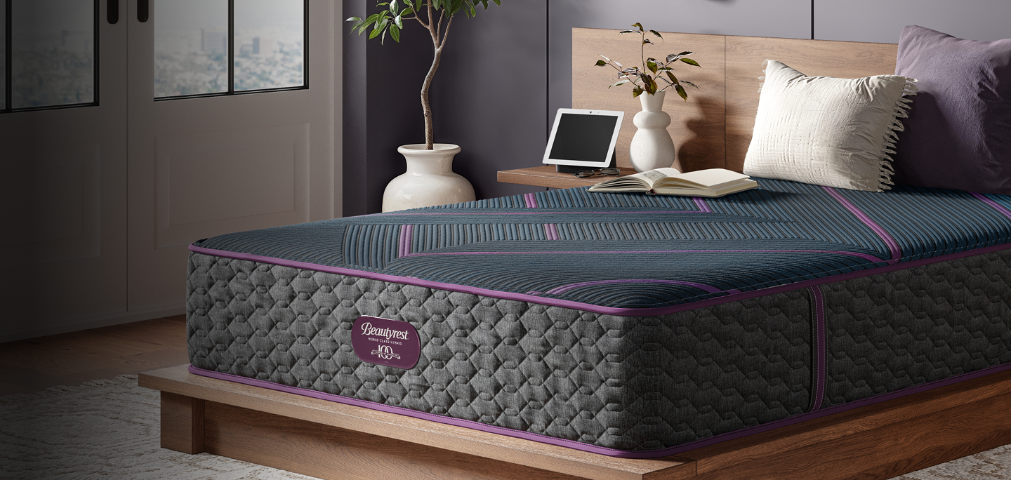 Beautyrest World Class Quilted Hybrid Level 3 mattress with 2 pillows and a book on top of it sitting on a brown bed frame